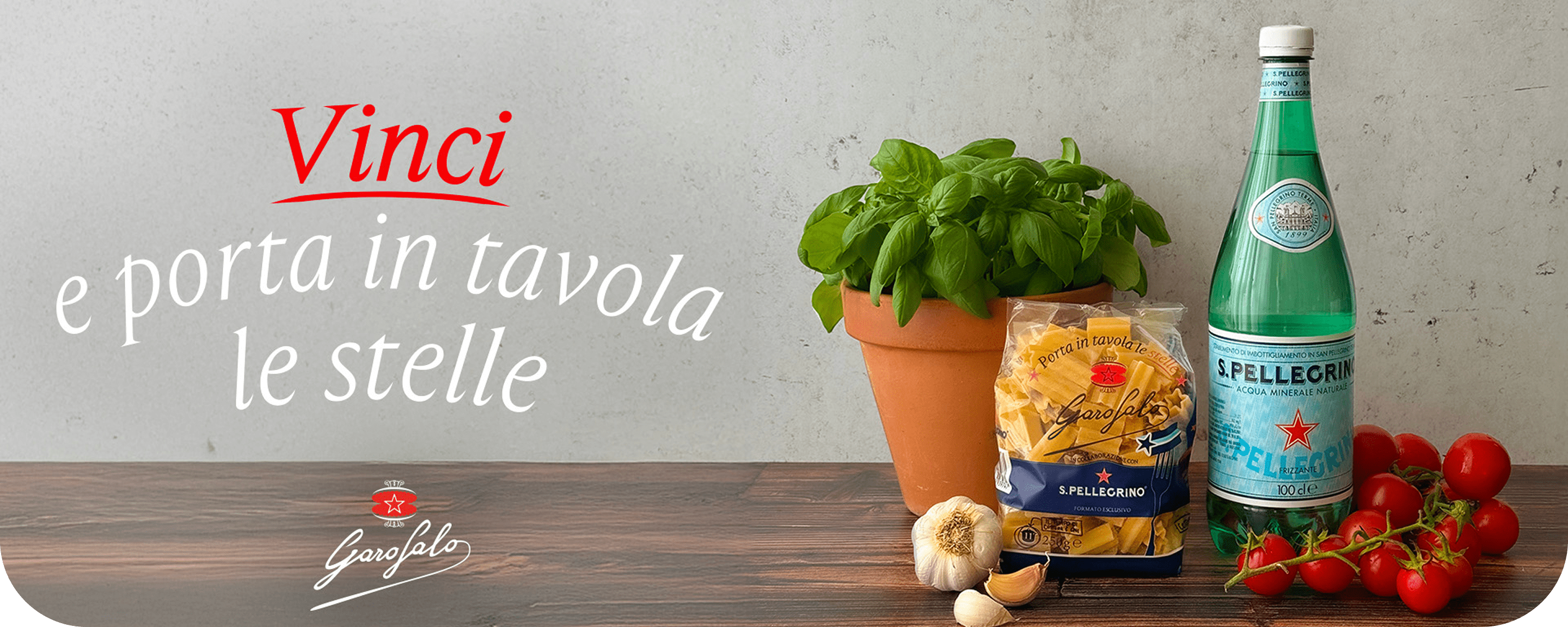 Una pianta di basilico, pasta Garofalo e una bottiglia San Pellegrino. In basso su una banda rossa il testo:'Vinci e porta in tavola le stelle'